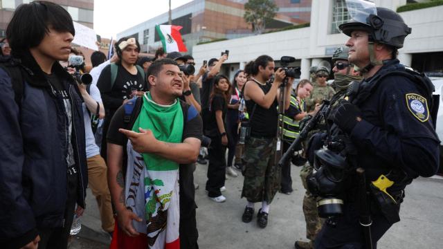 Un manifestante hace un gesto mientras agentes del orden hacen guardia mientras continúan las protestas contra las redadas federales de inmigración en Los Ángeles, California, EEUU.